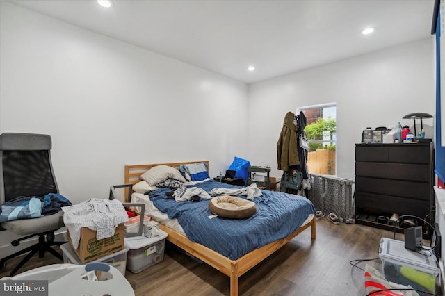 bedroom with dark hardwood / wood-style floors and radiator heating unit