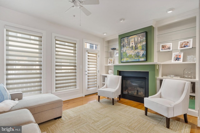 living area with ceiling fan, hardwood / wood-style flooring, a healthy amount of sunlight, and built in features