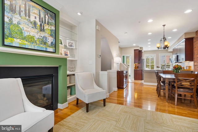 sitting room featuring an inviting chandelier, light hardwood / wood-style flooring, and a large fireplace