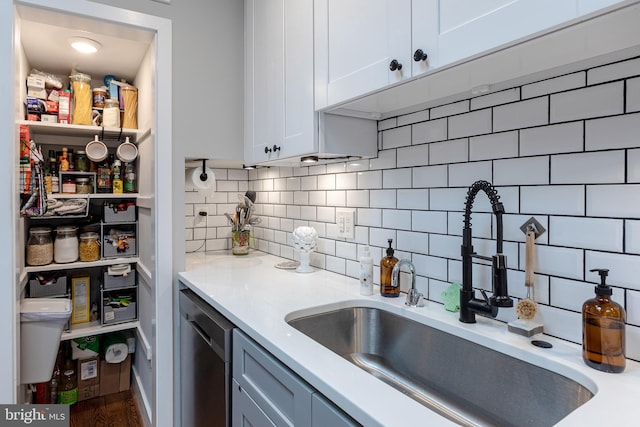 kitchen featuring wood-type flooring, sink, stainless steel dishwasher, backsplash, and white cabinetry