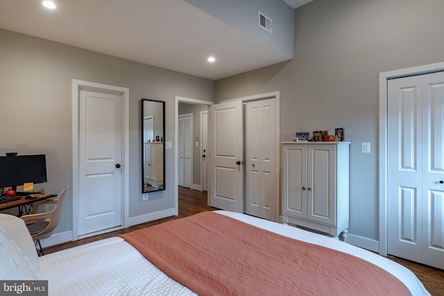 bedroom with dark wood-type flooring and multiple closets