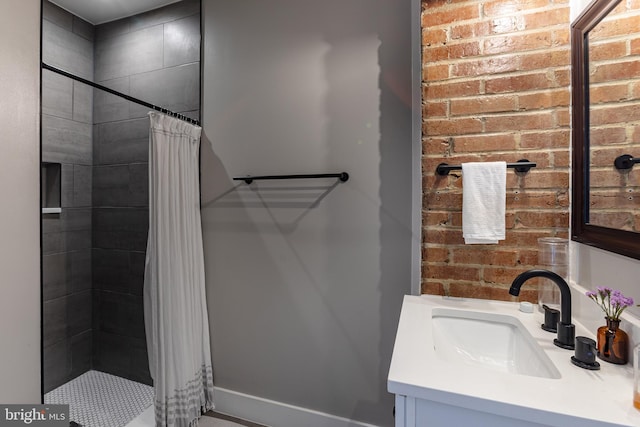 bathroom with vanity, a shower with shower curtain, and brick wall