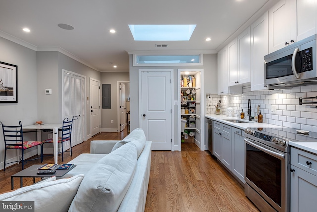 kitchen with crown molding, stainless steel appliances, light wood-type flooring, sink, and white cabinets