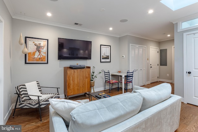 living room with a skylight, hardwood / wood-style flooring, and ornamental molding