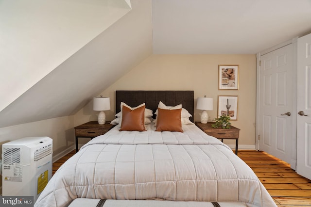 bedroom with vaulted ceiling, a closet, and hardwood / wood-style floors