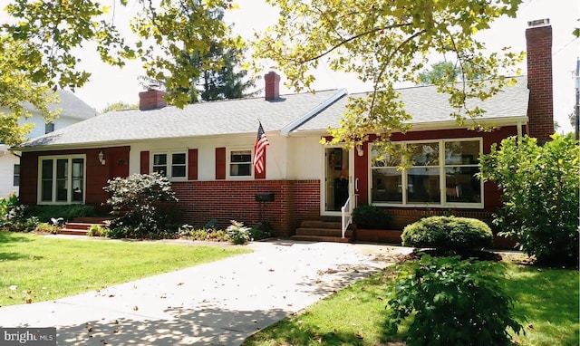 single story home featuring a front yard, brick siding, roof with shingles, and a chimney