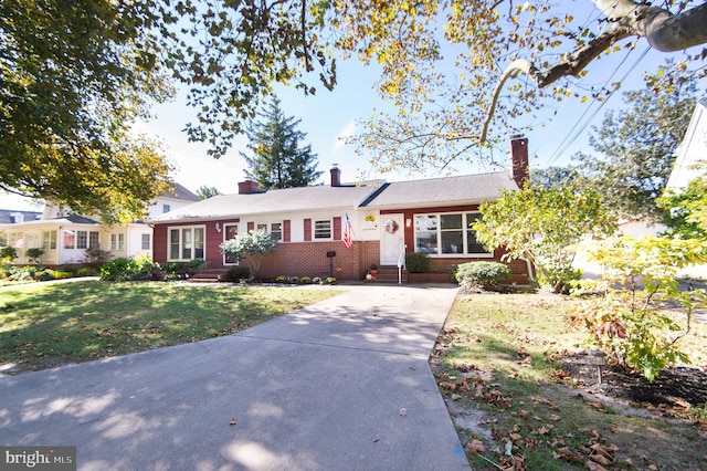 ranch-style home featuring a front lawn, a chimney, brick siding, concrete driveway, and entry steps