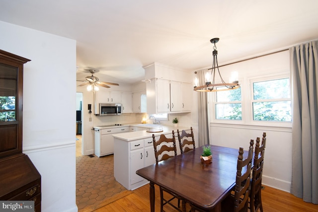 dining room featuring sink, ceiling fan with notable chandelier, and light hardwood / wood-style floors