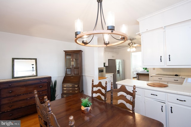 dining space featuring ceiling fan with notable chandelier and light hardwood / wood-style floors