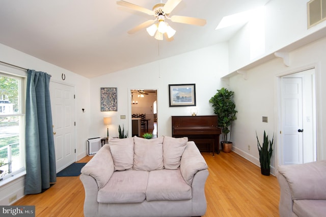 living room with lofted ceiling with skylight, light hardwood / wood-style flooring, and ceiling fan