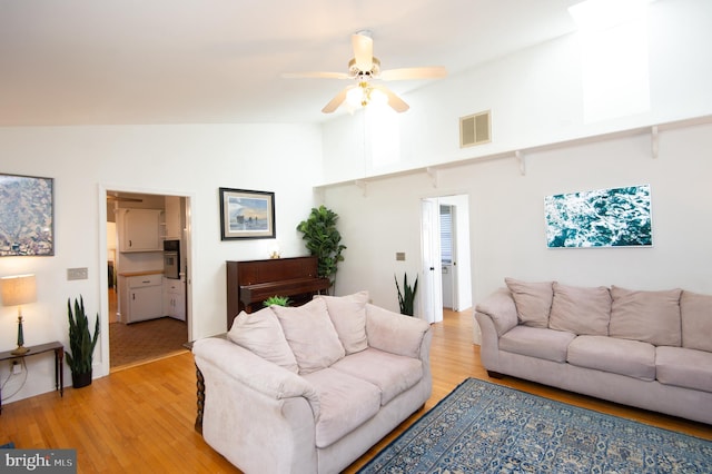 living room with light hardwood / wood-style floors, high vaulted ceiling, and ceiling fan