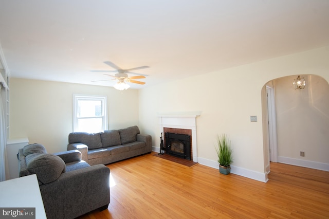 living room featuring a fireplace, light wood-type flooring, and ceiling fan