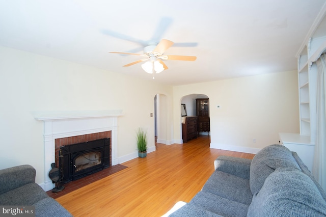 living room featuring a fireplace, wood-type flooring, and ceiling fan