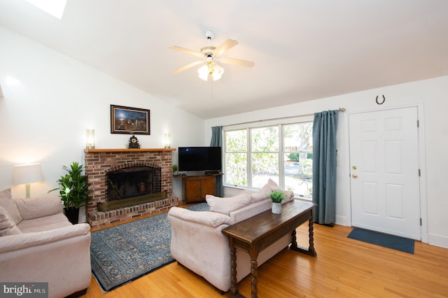 living room with lofted ceiling with skylight, hardwood / wood-style flooring, a fireplace, and ceiling fan