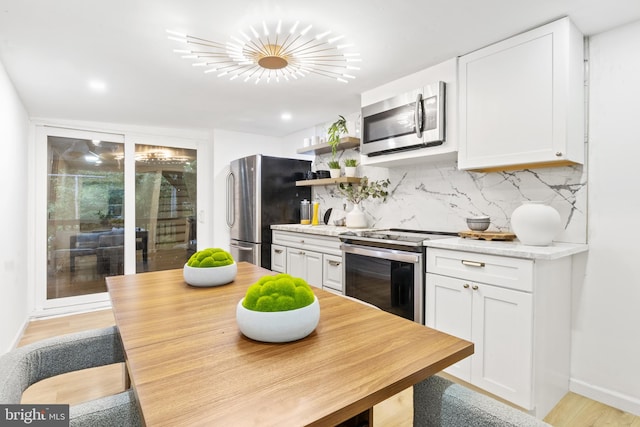 kitchen featuring decorative backsplash, stainless steel appliances, white cabinets, and light hardwood / wood-style floors