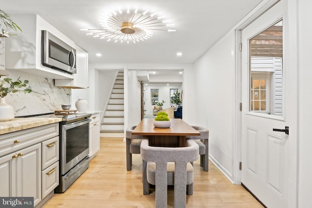 kitchen featuring decorative backsplash, light hardwood / wood-style flooring, stainless steel appliances, and white cabinets