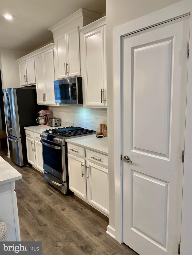 kitchen featuring backsplash, stainless steel appliances, white cabinets, and dark hardwood / wood-style flooring