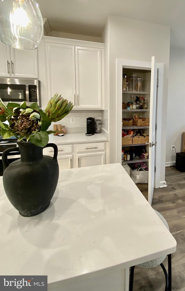 interior space with dark wood-type flooring, white cabinetry, and decorative backsplash