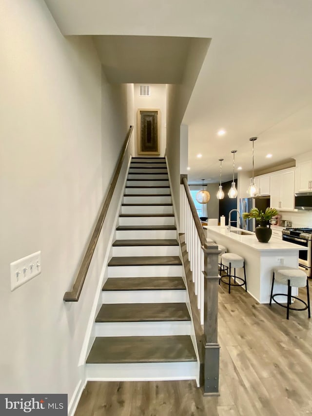 staircase featuring hardwood / wood-style flooring and sink