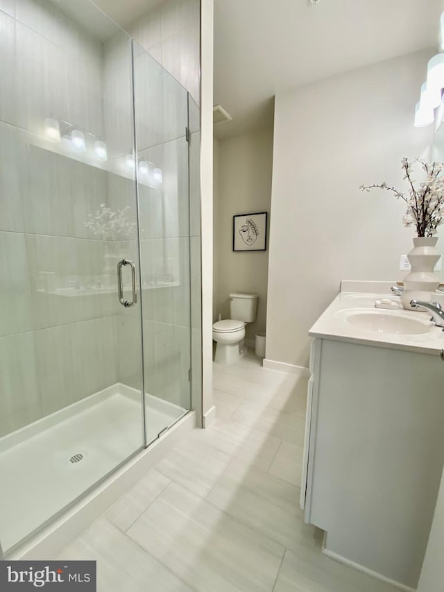 bathroom featuring vanity, tile patterned floors, a shower with shower door, and toilet