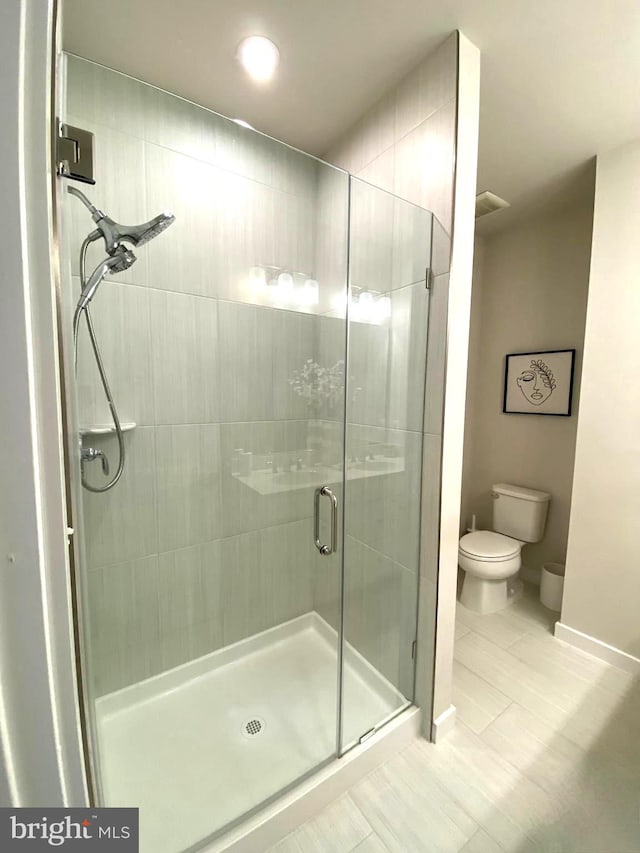 bathroom with toilet and an enclosed shower