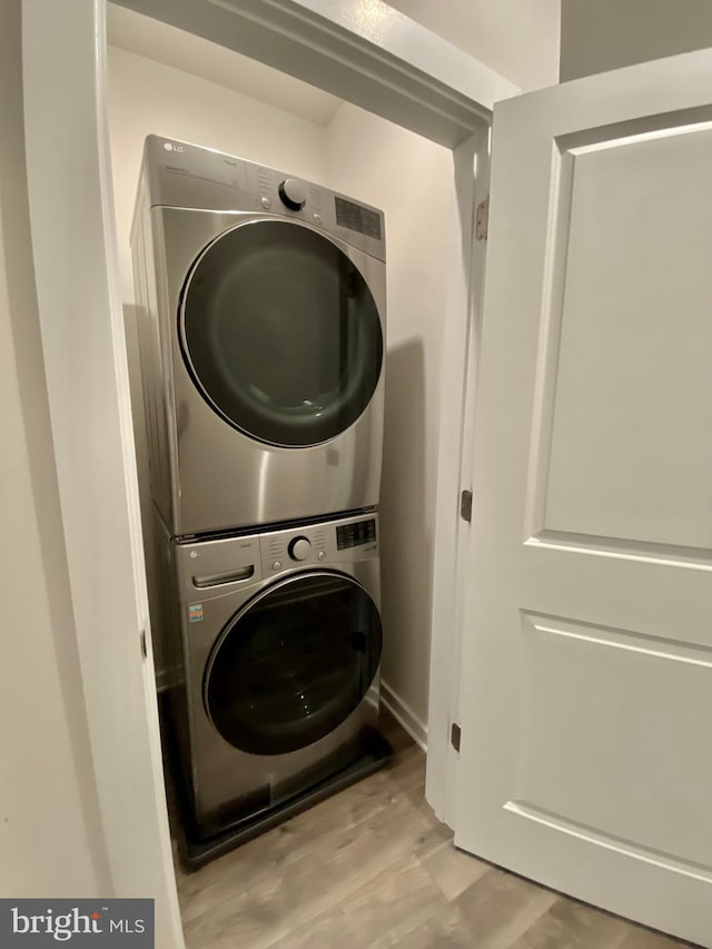 clothes washing area with light hardwood / wood-style flooring and stacked washer / dryer