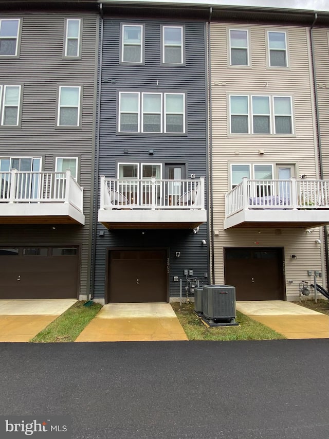 back of property with a balcony, cooling unit, and a garage