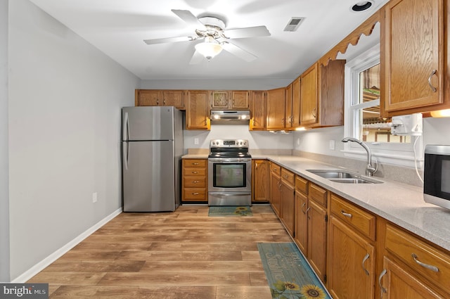 kitchen with appliances with stainless steel finishes, light wood-type flooring, sink, and ceiling fan