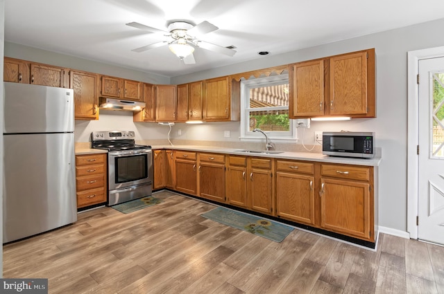 kitchen featuring ceiling fan, appliances with stainless steel finishes, light wood-type flooring, and sink