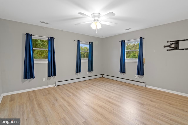 unfurnished room featuring light hardwood / wood-style flooring, a baseboard heating unit, ceiling fan, and a healthy amount of sunlight