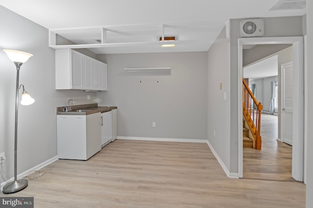 kitchen with dishwasher, sink, light hardwood / wood-style floors, and white cabinetry