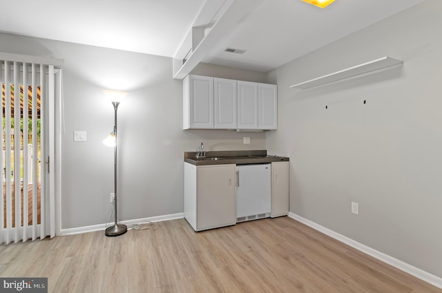 kitchen with light wood-type flooring, white cabinetry, dishwasher, and sink