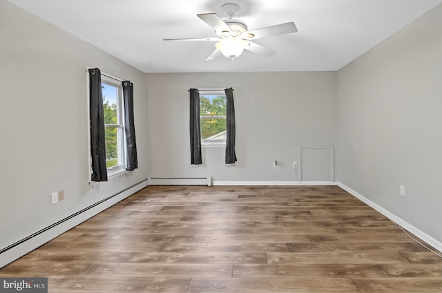 spare room featuring a baseboard heating unit, ceiling fan, and hardwood / wood-style flooring