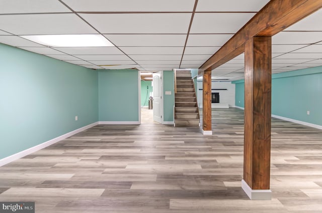 basement with a drop ceiling and light wood-type flooring