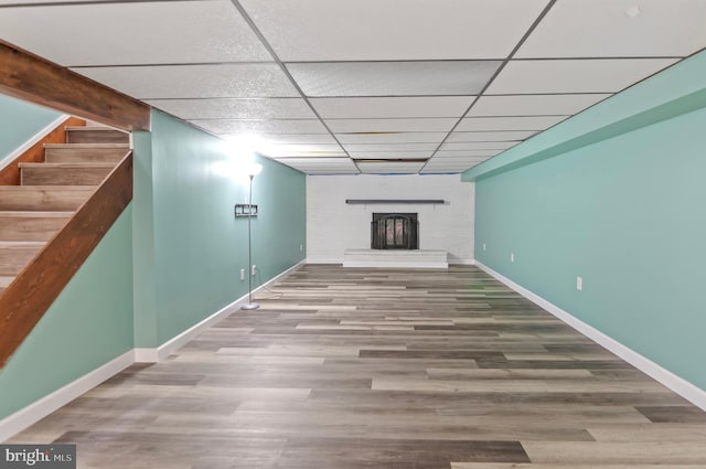 basement featuring a fireplace, a paneled ceiling, and hardwood / wood-style floors