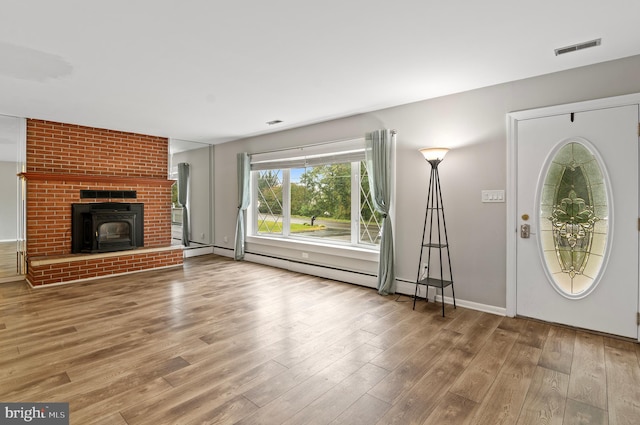 foyer with a brick fireplace, hardwood / wood-style flooring, and baseboard heating