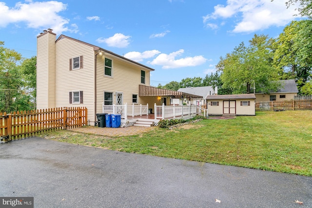 back of property with a wooden deck, a shed, and a lawn