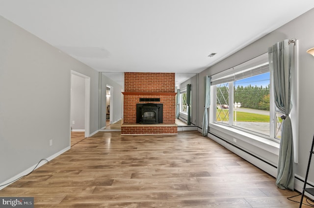 unfurnished living room with a fireplace, a baseboard heating unit, and light hardwood / wood-style flooring