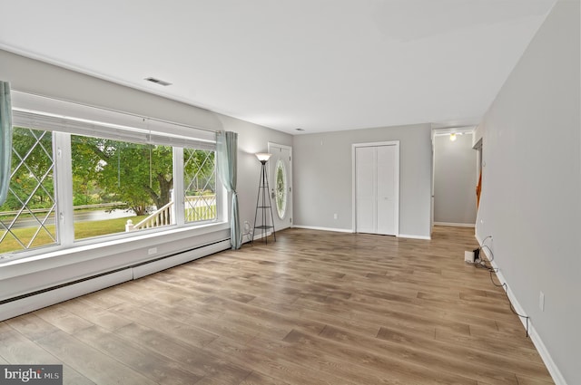 unfurnished living room featuring hardwood / wood-style floors and a baseboard heating unit