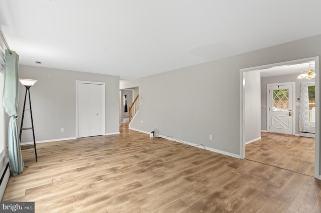 unfurnished living room with a notable chandelier, light hardwood / wood-style floors, and a baseboard radiator