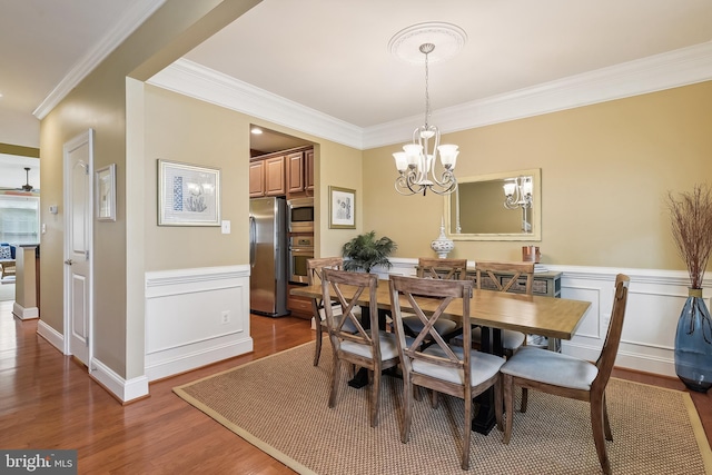 dining space featuring ornamental molding, a notable chandelier, and dark wood-type flooring