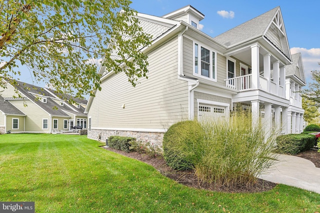 view of side of property featuring a yard, a balcony, and a garage