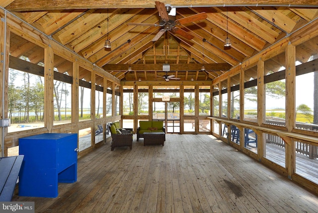 unfurnished sunroom with ceiling fan, vaulted ceiling with beams, and a healthy amount of sunlight