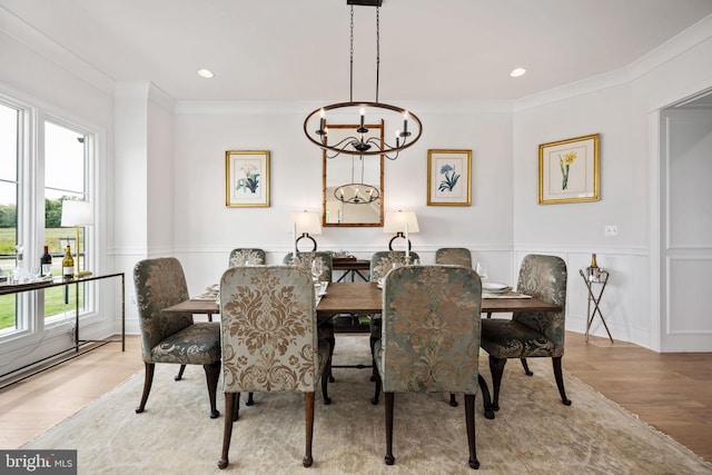 dining space with ornamental molding, an inviting chandelier, and light hardwood / wood-style floors