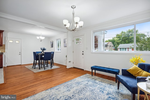 entrance foyer featuring a notable chandelier, light wood-type flooring, and ornamental molding