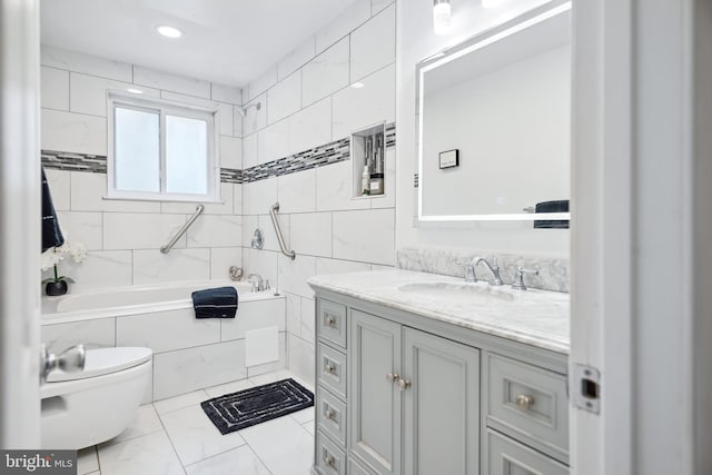 full bathroom with tile walls, tiled shower / bath combo, vanity, and toilet