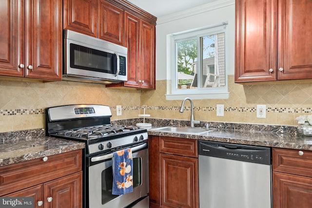 kitchen featuring tasteful backsplash, sink, stainless steel appliances, crown molding, and dark stone countertops