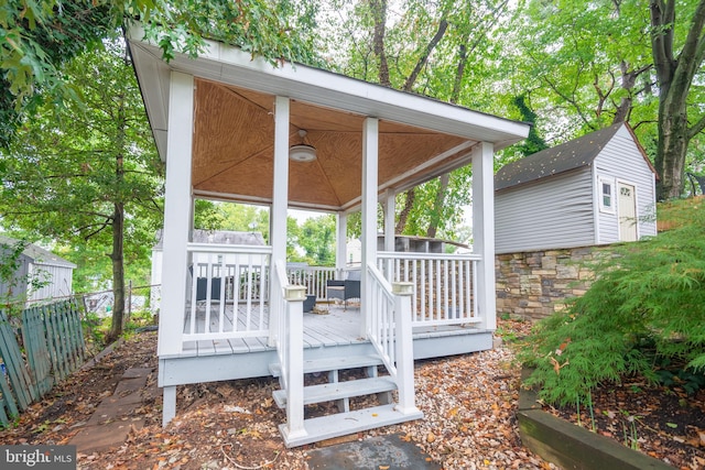 wooden deck with ceiling fan and an outdoor structure