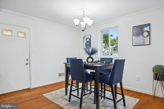 dining space featuring an inviting chandelier, hardwood / wood-style flooring, and ornamental molding