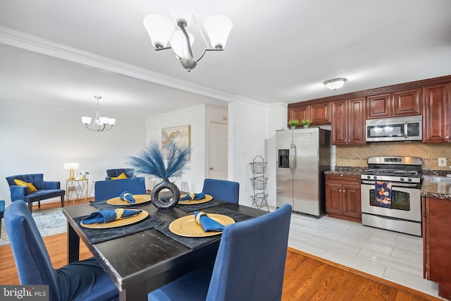 dining space featuring light wood-type flooring, crown molding, and a chandelier